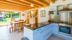 A modern kitchen with a central island, stainless steel appliances, and wooden beams on the ceiling.