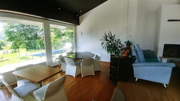 Ein modernes Wohnzimmer mit rundem Tisch, weißen Stühlen, einem blauen Sofa und einer großen Topfpflanze.