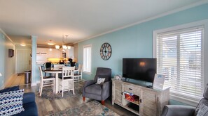 A living room with a TV, a sofa, and a dining area with a table and chairs.