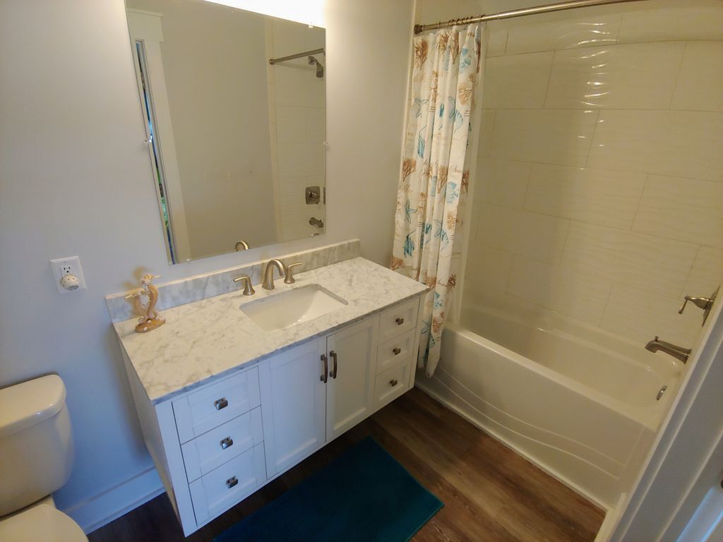 Een badkamer met een witte wastafel, spiegel en bad.