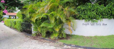 Un sendero conduce a una pared blanca con un letrero que dice 'Foyers Welt Bay House'.