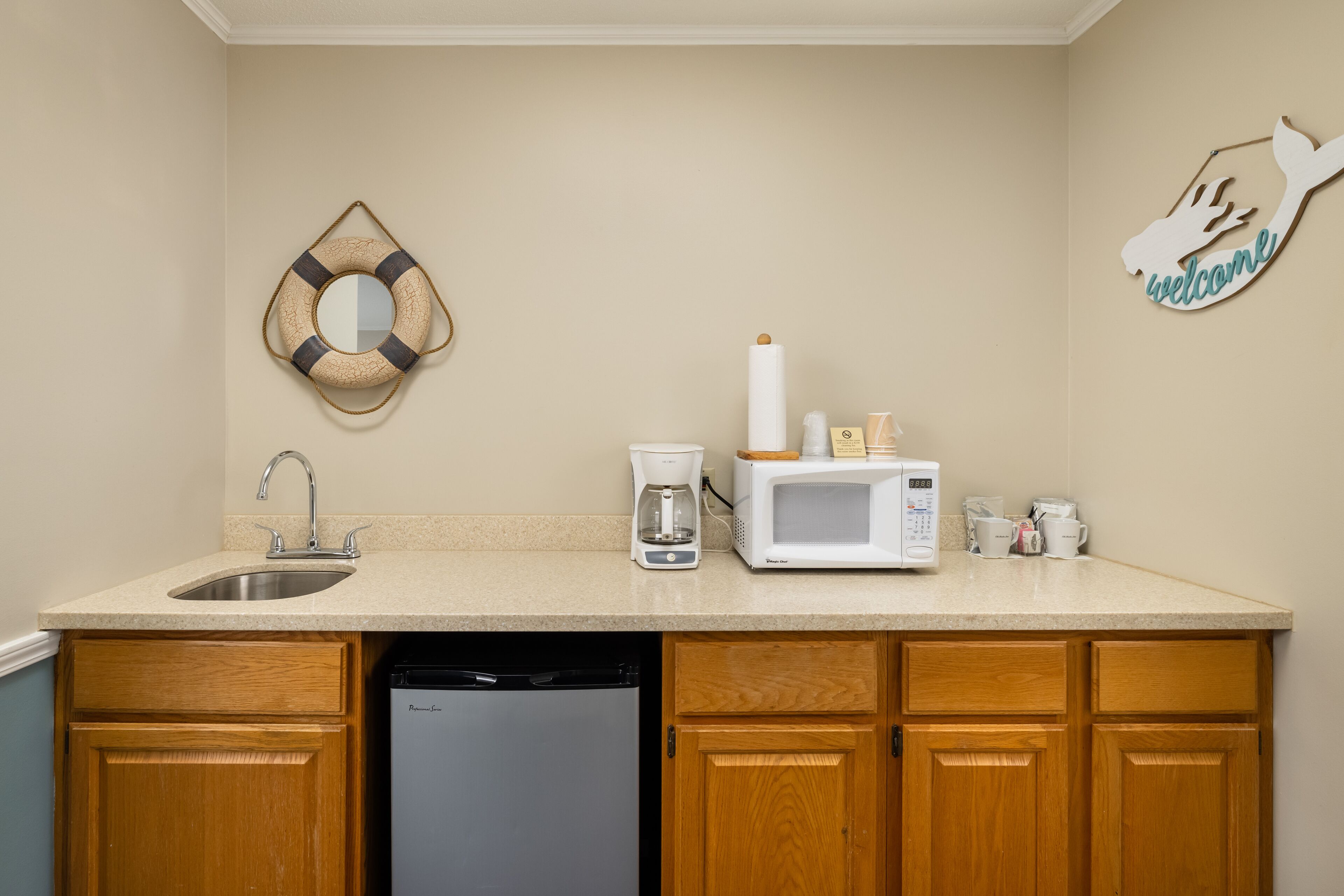 A kitchen with a sink, coffee maker, microwave, and wooden cabinets.