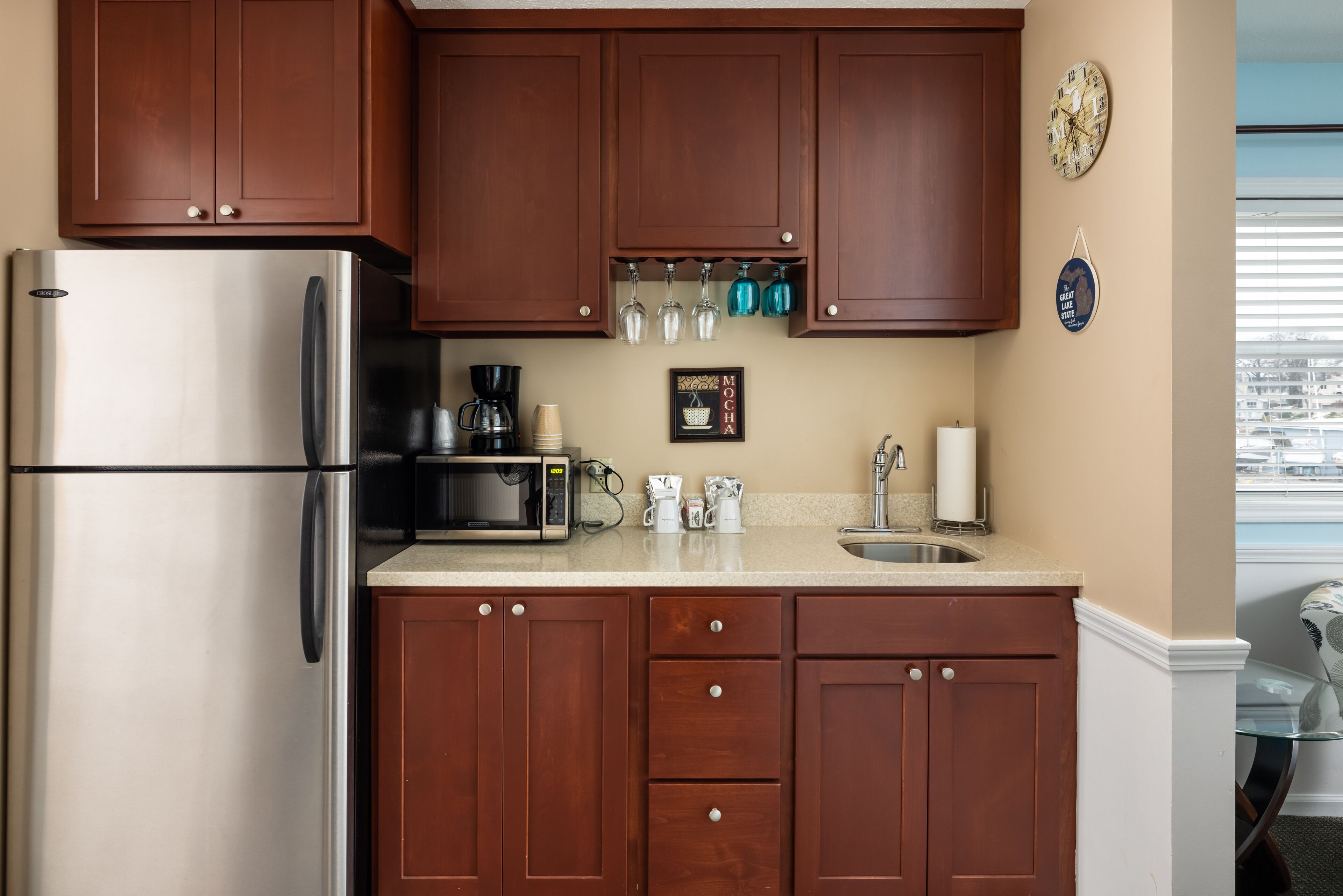 A kitchen with wooden cabinets, a stainless steel refrigerator, a microwave, and a coffee maker.