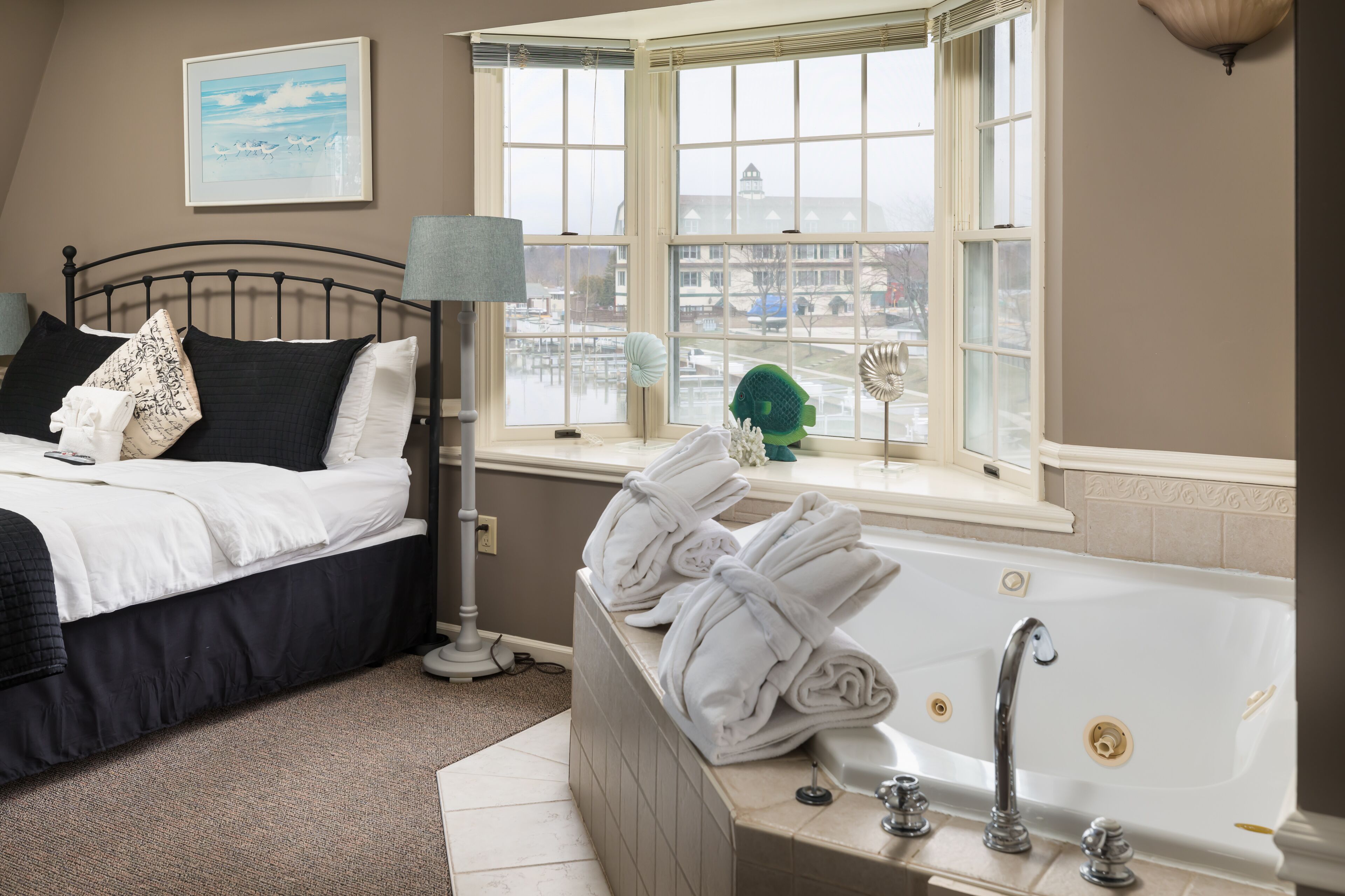 Une chambre d’hôtel avec un lit, une fenêtre donnant sur la ville, une baignoire et une lampe.