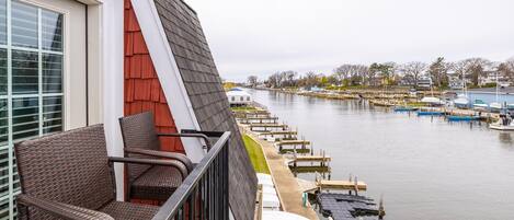 A balcony with wicker furniture overlooking a marina with boats docked.