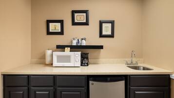 A kitchen with a microwave, coffee maker, and sink. There are framed certificates on the wall.