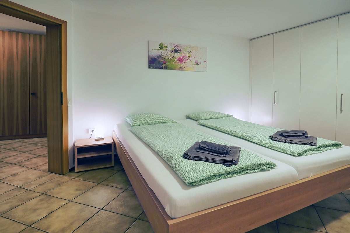 A room with a bed, a nightstand, a painting, and a wardrobe.