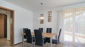A dining area with a wooden table and black chairs, a pendant light, and artwork on the wall. - APART HOLIDAYS Residenza Flora (Muralto)