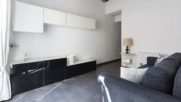 Une pièce moderne avec un meuble noir et blanc, un canapé gris et une lampe.