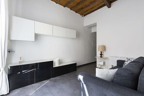 Una habitación moderna con un mueble negro y blanco, un sofá gris y una lámpara.