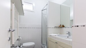 Een badkamer met toilet, wastafel, douche en een spiegel.