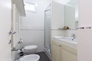 Ein Badezimmer mit Toilette, Waschbecken, Dusche und Spiegel.