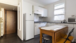 Une cuisine moderne avec des meubles blancs, une table en bois et un four à micro-ondes.