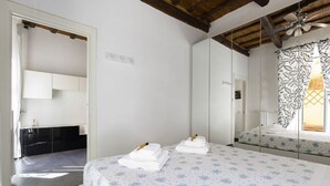 Een slaapkamer met een bed, een spiegel, een kledingkast en een badkamer, zichtbaar door een geopende deur.