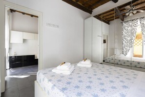 Ein Schlafzimmer mit Bett, Spiegel, Kleiderschrank und angrenzendem Badezimmer.