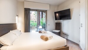 Een hotelkamer met een bed, een aan de muur bevestigde televisie en een schuifglazen deur naar een buitenruimte.