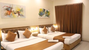 A hotel room with two beds, brown headboards, white linens, and two abstract paintings on the walls. - Hotel Grandeur (Mumbai)