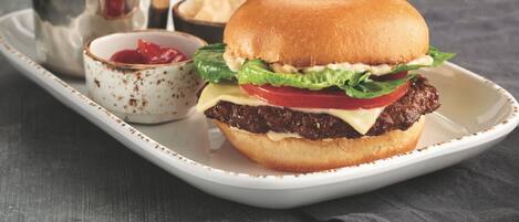 A burger with lettuce, tomato, and cheese on a bun, served with fries and ketchup.