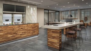 A modern bar area with a wooden counter, bar stools, and a seating area with a table and chairs. - Courtyard by Marriott Portland East (Portland)