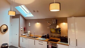 A modern kitchen with a skylight, pendant lights, a built-in oven, and a stainless steel sink.