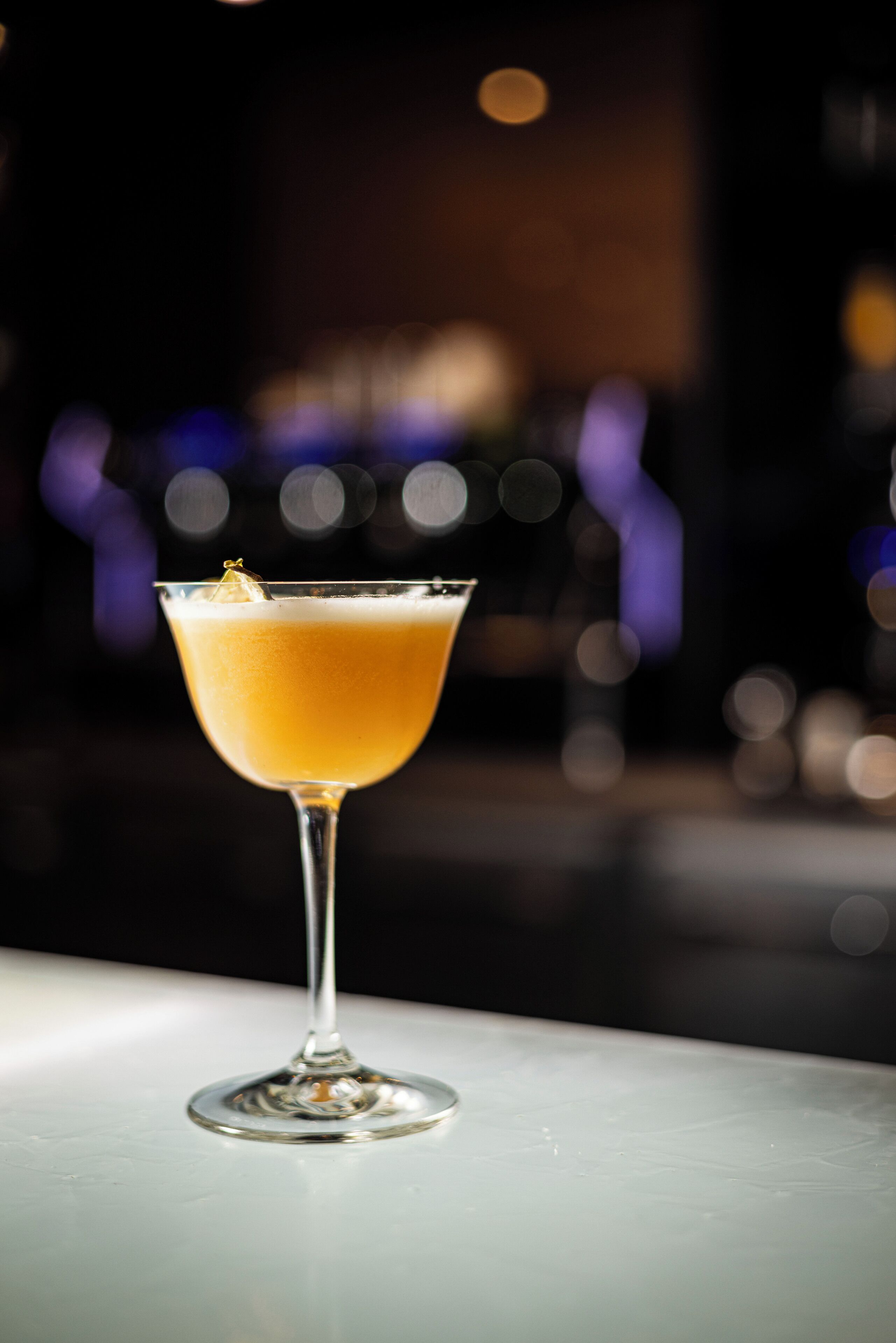Um coquetel num copo de martini sobre uma superfície branca.