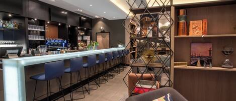 Eine moderne Bar mit einer langen Theke, blauen Barhocker und einer dekorativen Metallabtrennung.