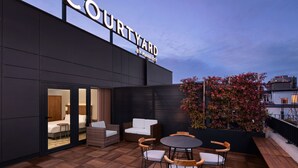Ein Courtyard by Marriott Hotel mit Außenbereich und Terrassenmöbeln, mit Blick auf die Stadt.