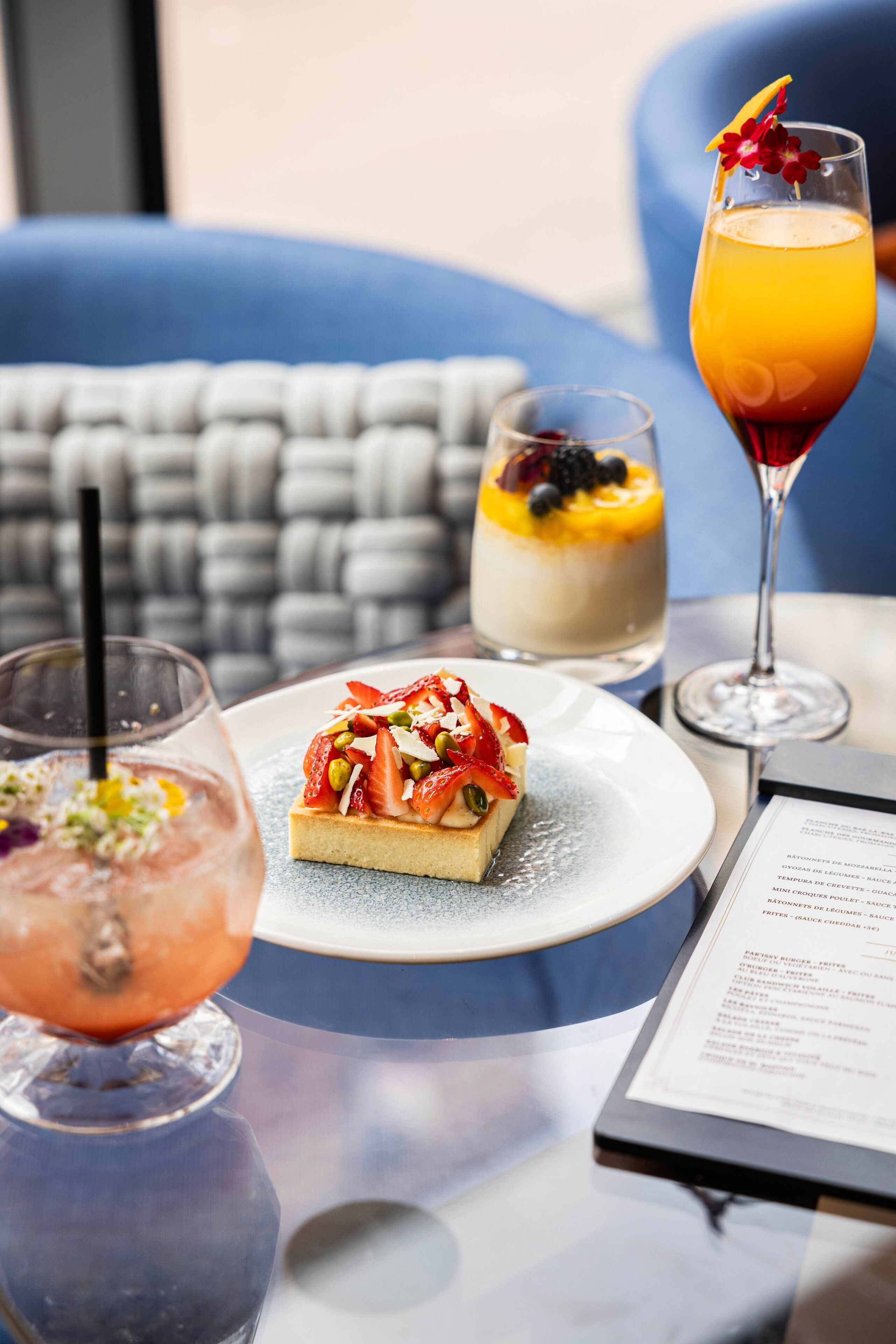 A table with a dessert, a cocktail, and a menu.