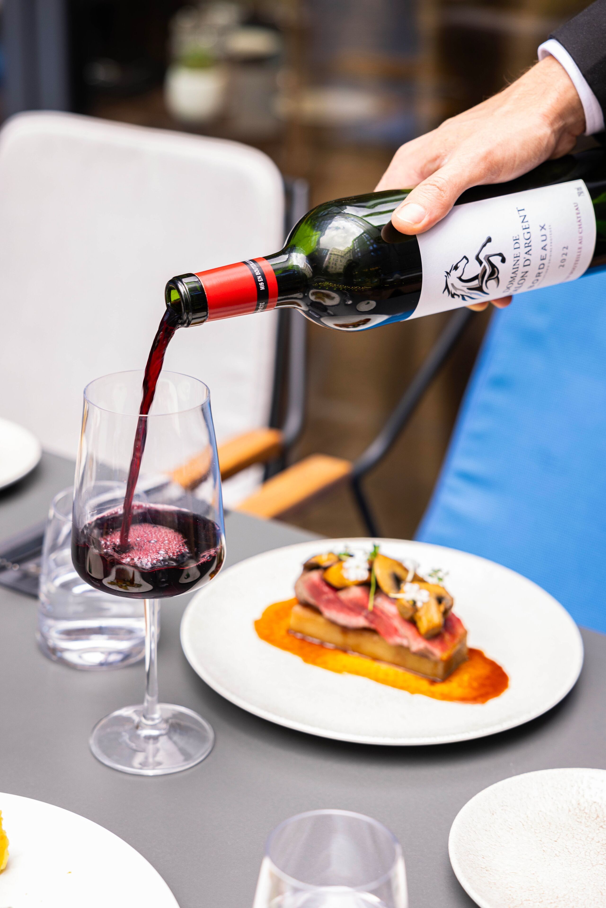 A person pouring red wine into a glass.