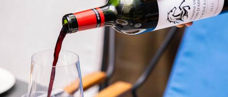 A person pouring red wine into a glass.
