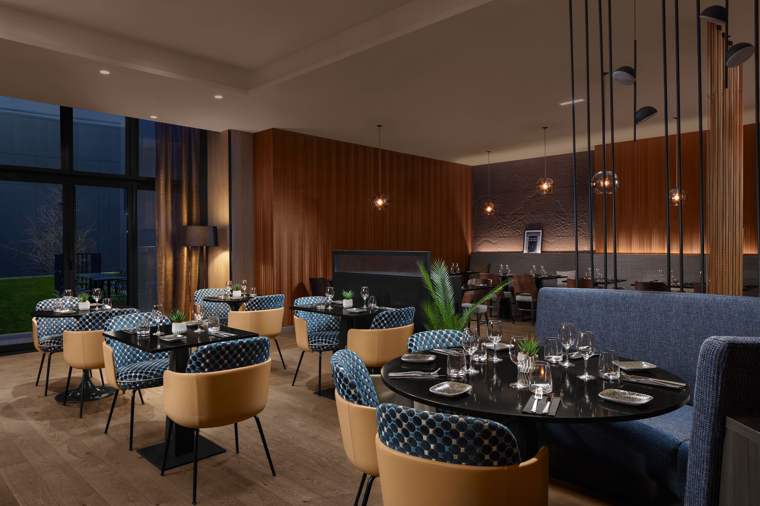 A modern dining area with round tables, blue patterned chairs, and a blue sofa.