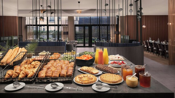 Ein Buffet mit verschiedenen Speisen und Getränken, moderne Beleuchtung und ein Blick ins Freie.