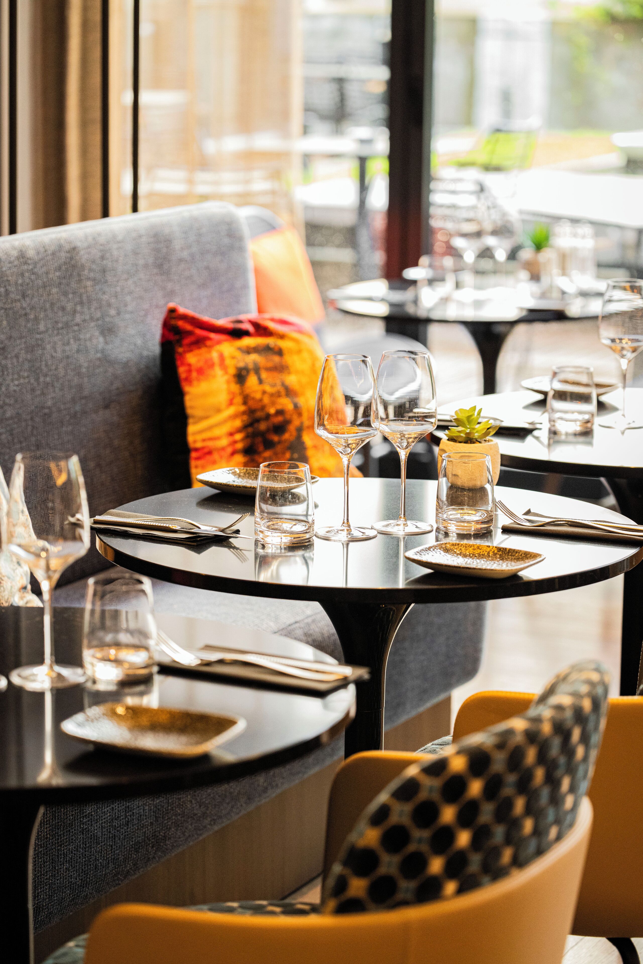 A dining area with tables set for two, featuring wine glasses, plates, and cutlery.