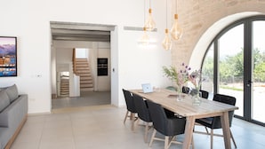 A modern dining area with a wooden table, black chairs, and hanging light fixtures. - Villa Annie - Luxury Villa - 360 Sea & White Mountains views - Luxury hamper  (Tsivaras)
