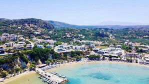 A coastal town with buildings on a hillside, a beach, and boats in the water. - Villa Annie - Luxury Villa - 360 Sea & White Mountains views - Luxury hamper  (Tsivaras)