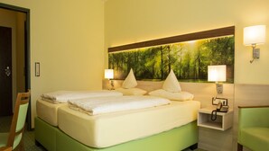 A hotel room with a large bed, two bedside tables, a nightstand, a chair, and a wall-mounted lamp. - Lampes Posthotel (Delligsen)