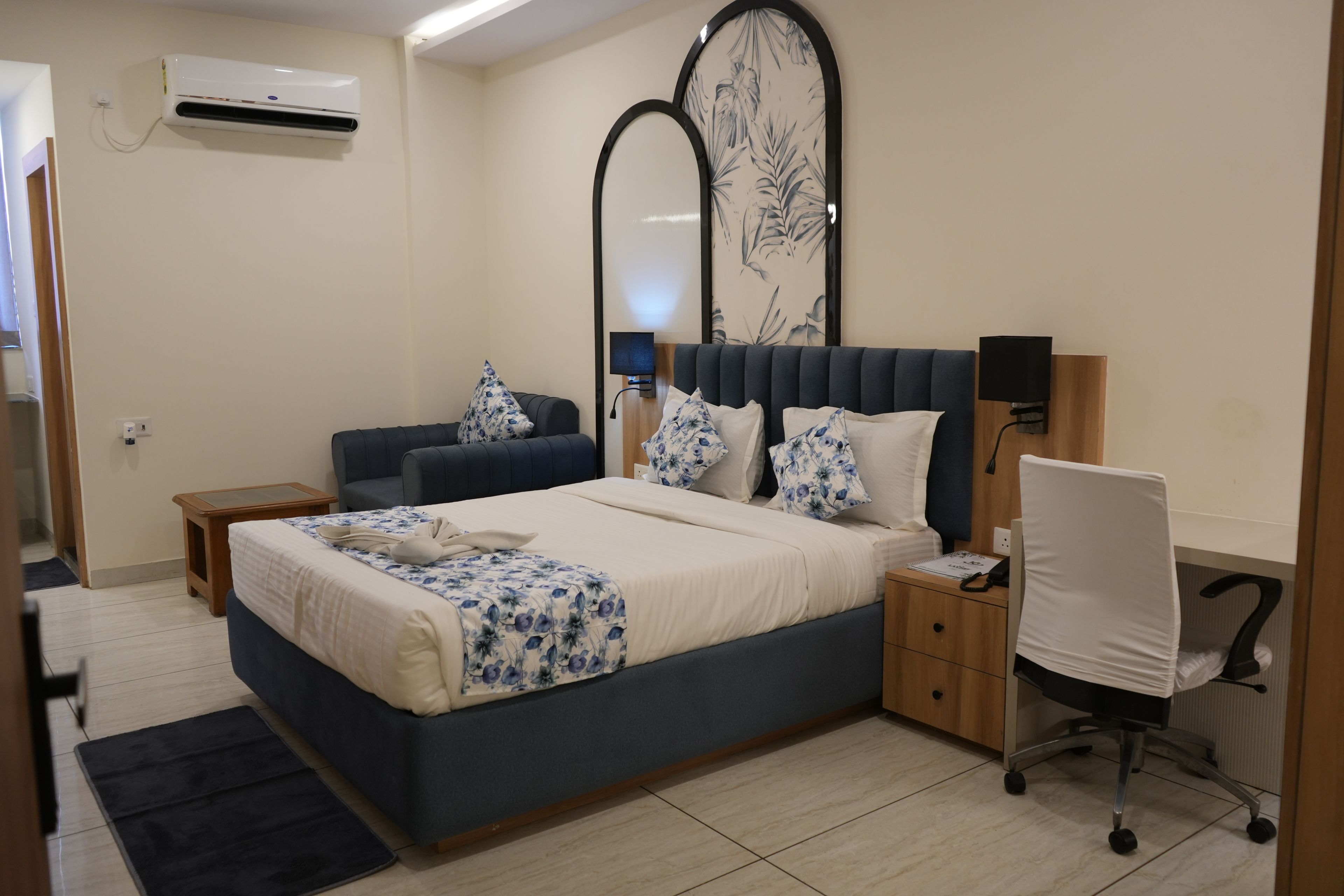 Une chambre à coucher comprenant un lit, un bureau, une chaise, une table de chevet, un miroir et un appareil de climatisation.