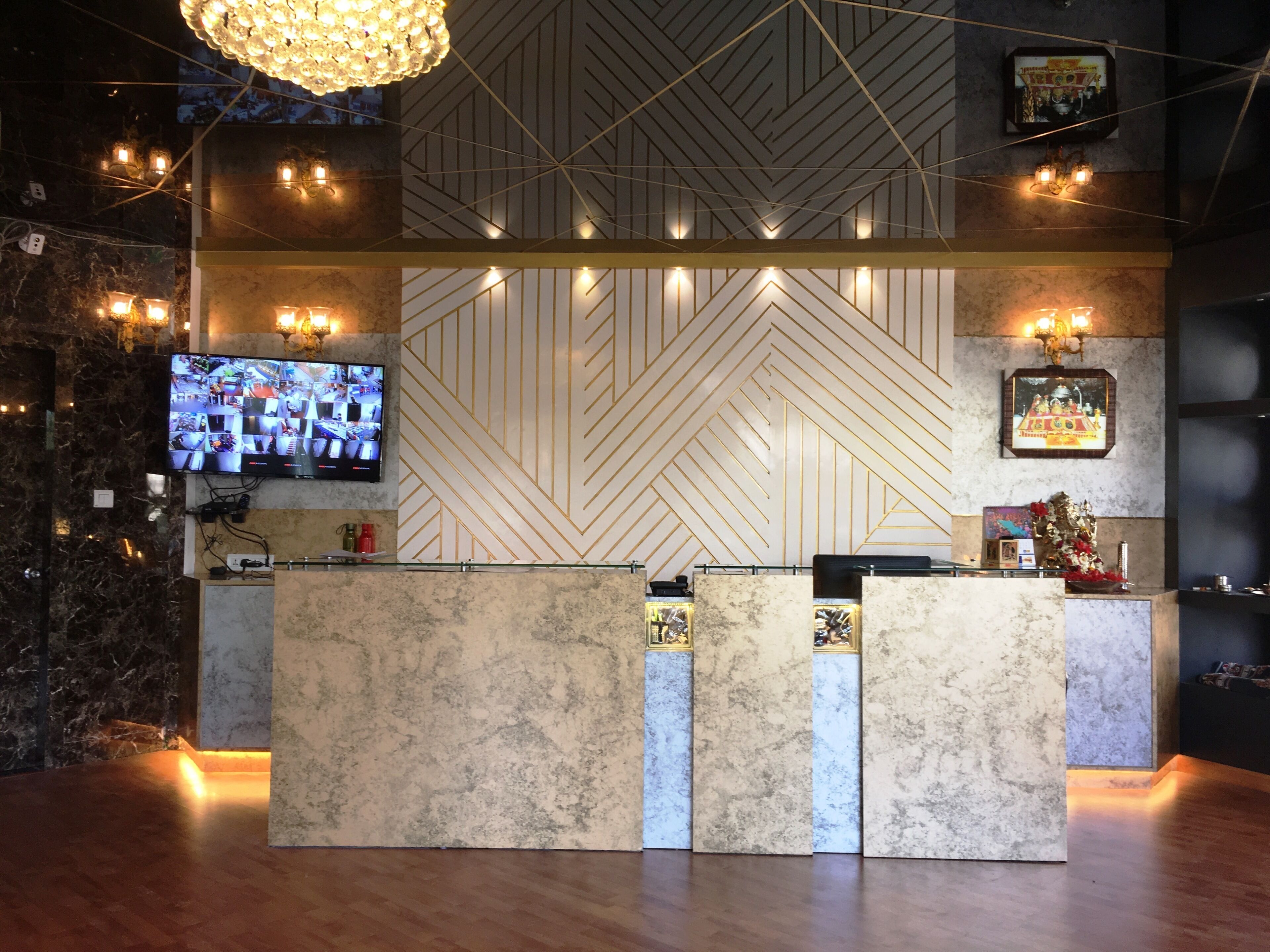 A reception desk with a marble counter, a television mounted on the wall, and a geometric patterned wall behind it.