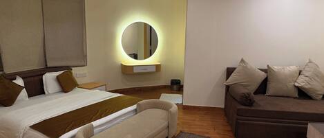 Un dormitorio moderno con cama, sofá, espejo y una pequeña mesa.