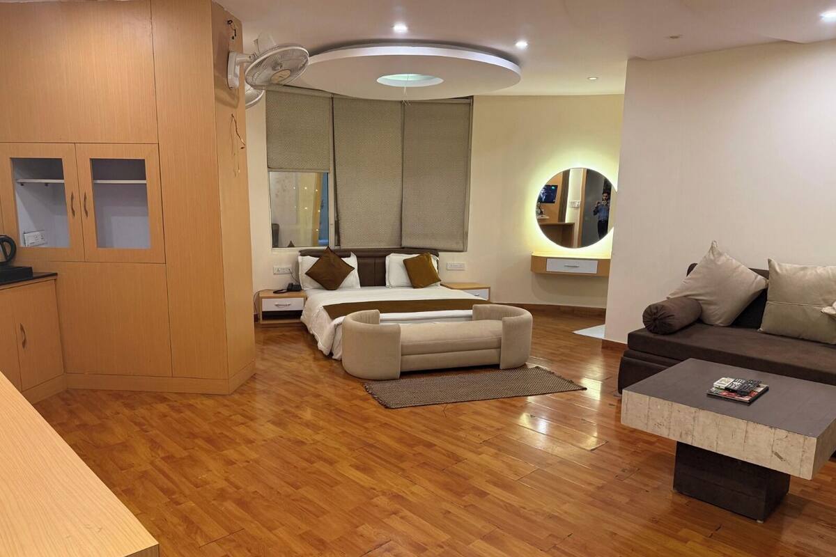 A modern living room with a sofa, a small coffee table, a bed with a headboard, and a wooden cabinet.