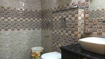A bathroom with a tiled shower wall, a toilet, and a sink with a black countertop.