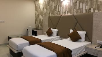 Una habitación de hotel moderna con dos camas, un escritorio y una pared con diseño imitación madera.