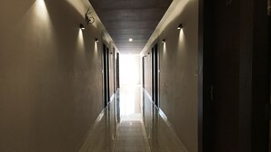 A long, well-lit corridor with a polished floor, leading to a bright exit. - Hotel K3 Club Residency (Jhansi)