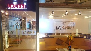 A modern interior with a sofa and a coffee table, a glass partition, and a sign reading "LA CHEF". - Hotel K3 Club Residency (Jhansi)