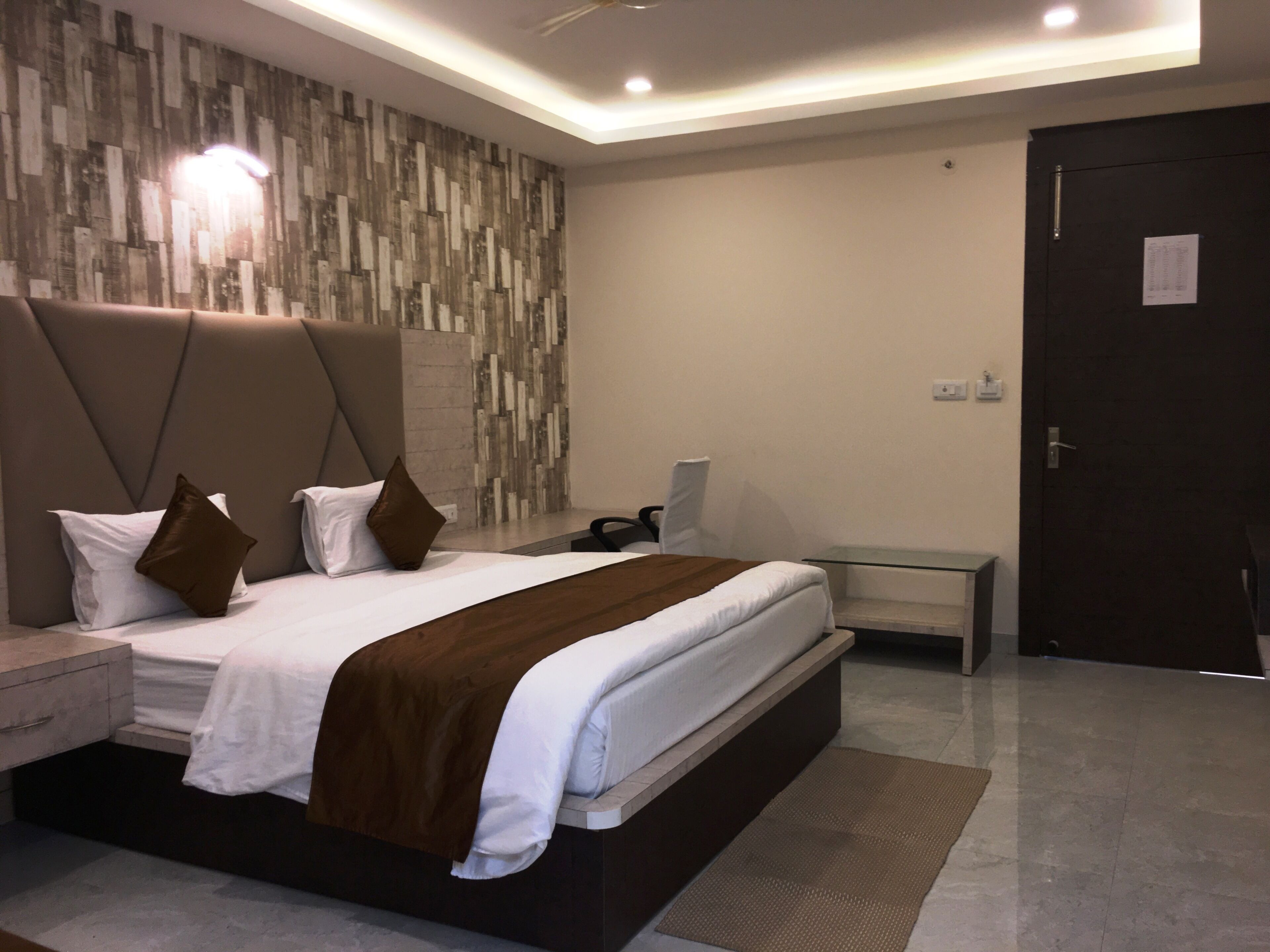 Quarto moderno com cama grande, mesa de cabeceira, escrivaninha e guarda-roupa.