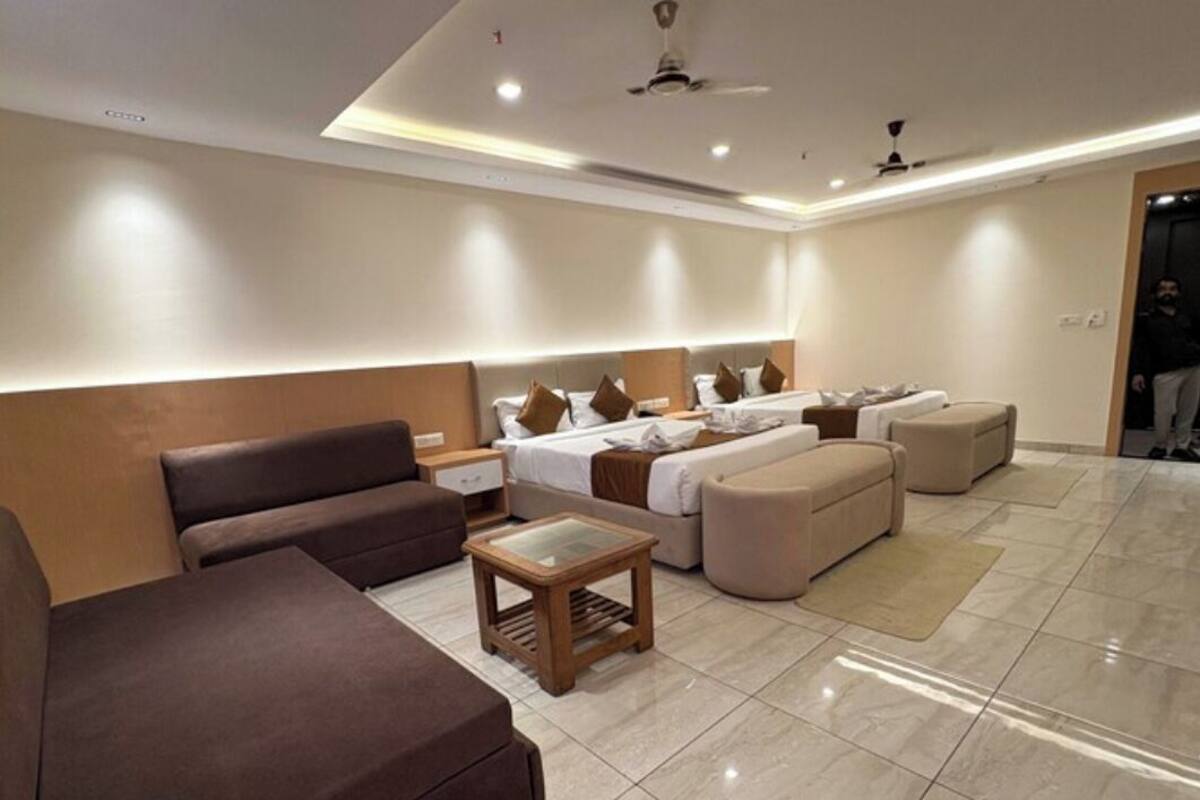 A modern hotel room with a sofa, ottoman, and a small table.