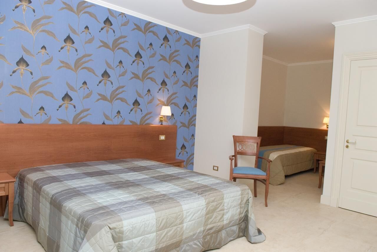 Una camera d'albergo con un letto grande, una poltrona, una scrivania e un tavolino.