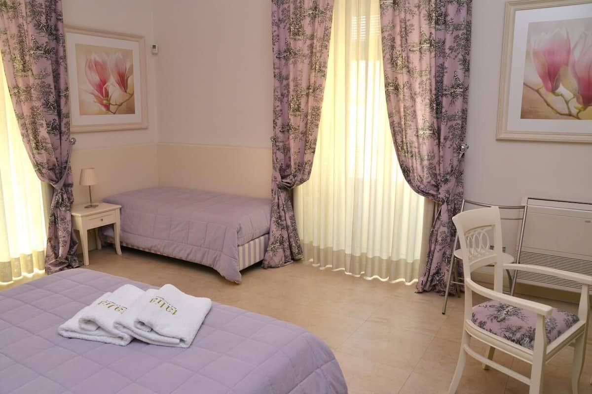 A bedroom with a bed, a nightstand, a chair, and a window with curtains.