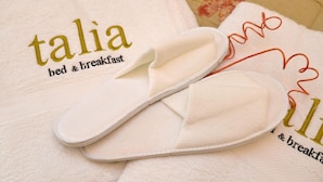 A pair of white slippers on a bed with a towel that reads "talia bed & breakfast". - B&B Talìa (Grammichele)