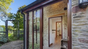 Un bâtiment en pierre avec une porte en verre donnant sur un espace cuisine.